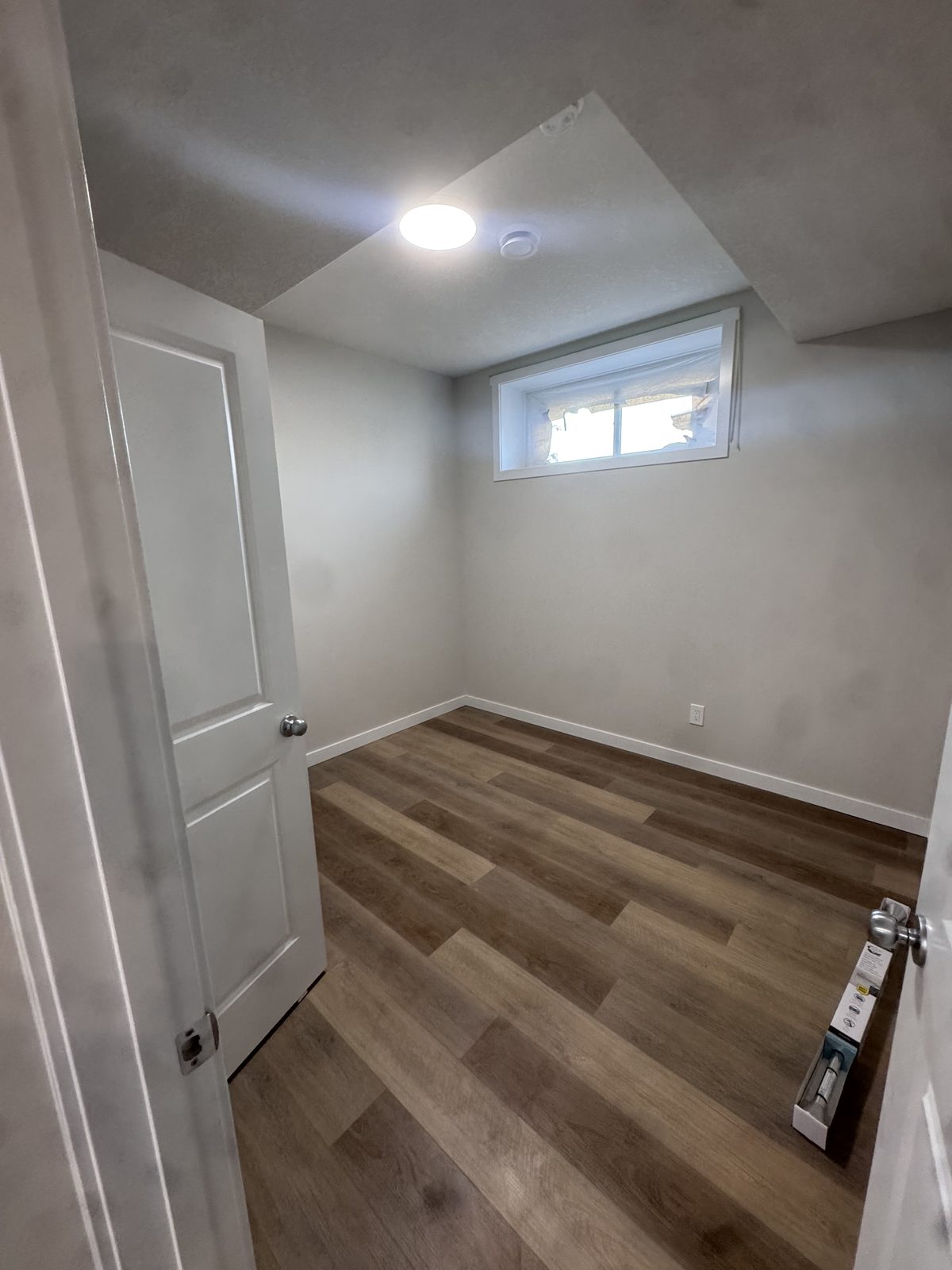 Finished basement bedroom with egress window and vinyl plank flooring